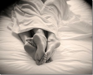 two pairs of feet sticking out from under bedsheet
