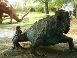 child eating apple while lounging on dinosaur sculpture